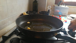 Pomodorini a metà in padella con aglio e acqua di cottura delle cozze