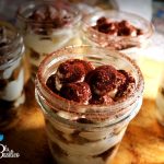 Tiramisù senza uova in un contenitore di vetro con strati di savoiardi al caffè e crema al mascarpone, spolverato di cacao
