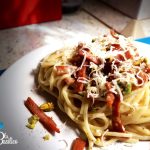 Piatto di spaghetti mantecati con provolone fuso, listarelle di mortadella croccante e granella di pistacchi