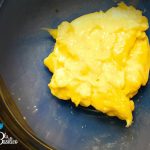 Ciotola di crema pasticcera gialla e vellutata con baccello di vaniglia e scorza di limone accanto