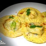 Ravioli fatti in casa con ripieno di patate e gamberoni, serviti su riduzione di teste di gambero con menta e finocchietto