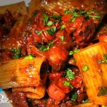 Rigatoni al ragù di polpo in una padella con pomodorini, olive taggiasche e prezzemolo tritato