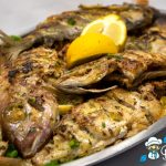 Grigliata di pesce misto con fragolini, mormore, triglie e saraghi servita su un vassoio con insalata e fettine di limone